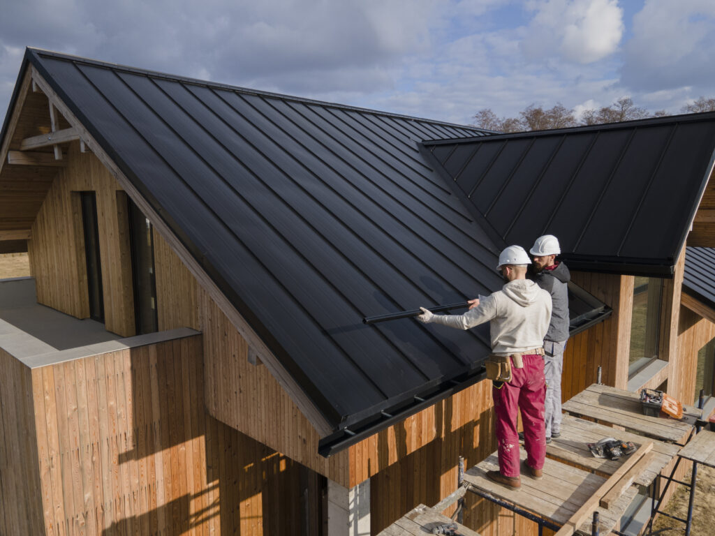 Builders installing roofing on a timber-framed home under construction.