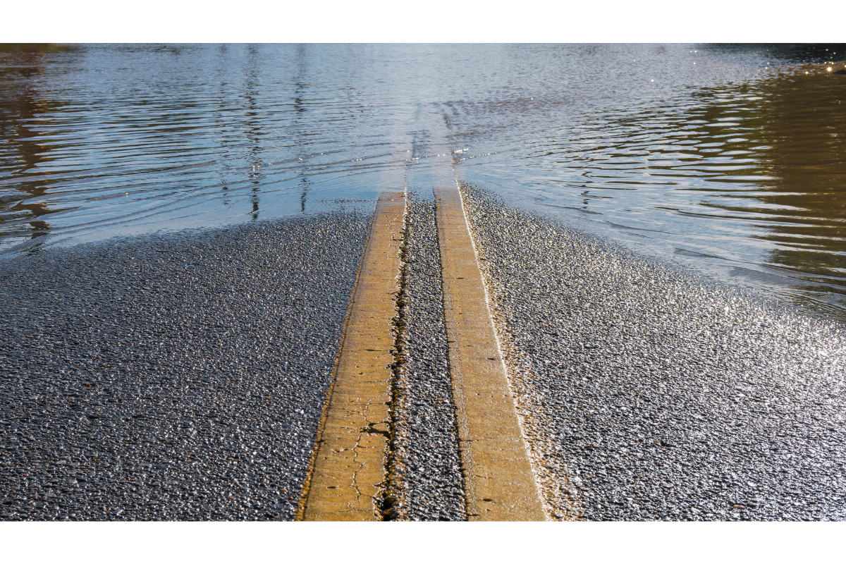 Flooded road surface showing the extent of water overflow, often affecting nearby properties, requiring home building inspections in Brisbane.