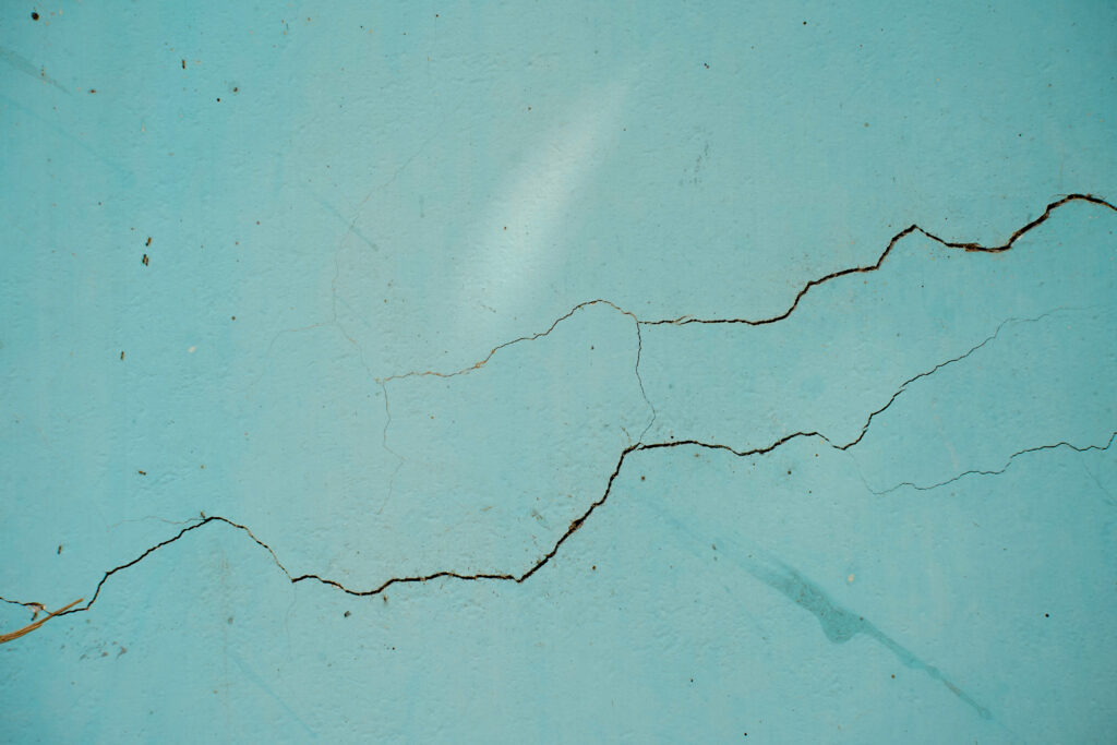 Hairline horizontal crack running across a painted rendered wall, a sign of possible structural movement