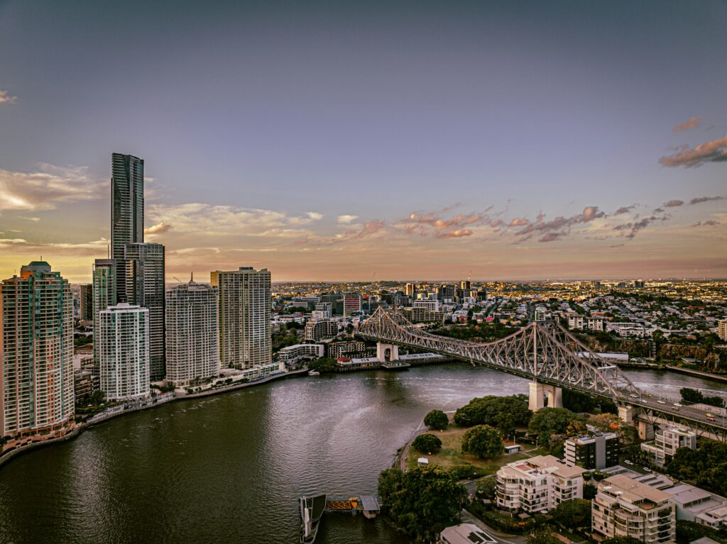 Aerial view of Brisbane city skyline and Story Bridge spanning the Brisbane River at sunset.
