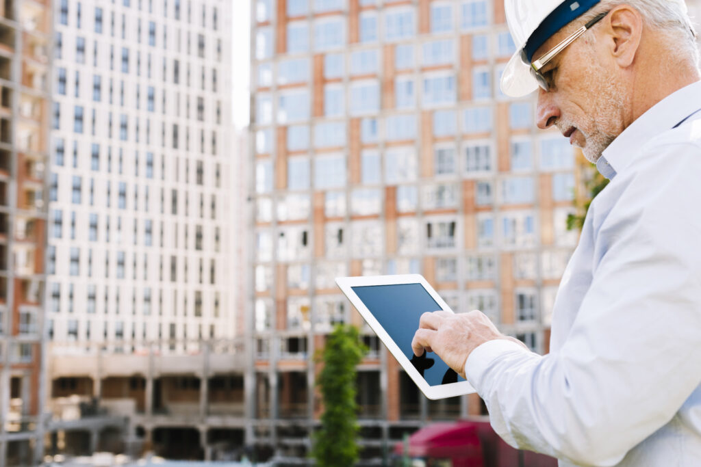 Building inspector using a tablet to assess a multi-storey apartment development.