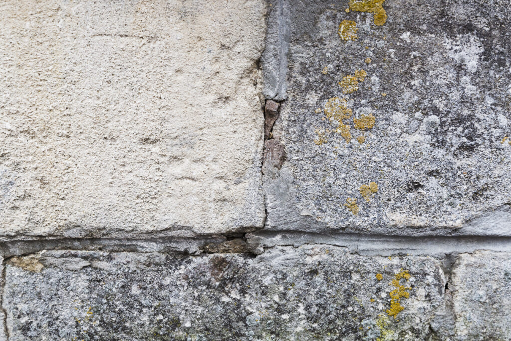 Cracked mortar and deteriorating masonry joints in a stone wall, indicating potential structural maintenance issues.