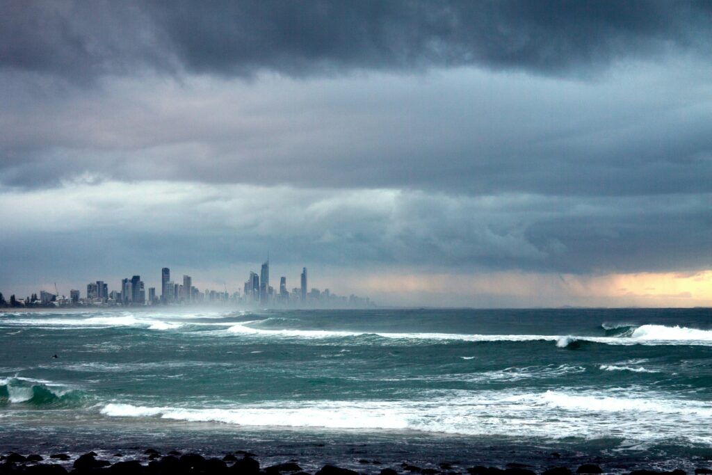 Dark storm clouds over rough ocean waves with Gold Coast skyline visible in the distance
