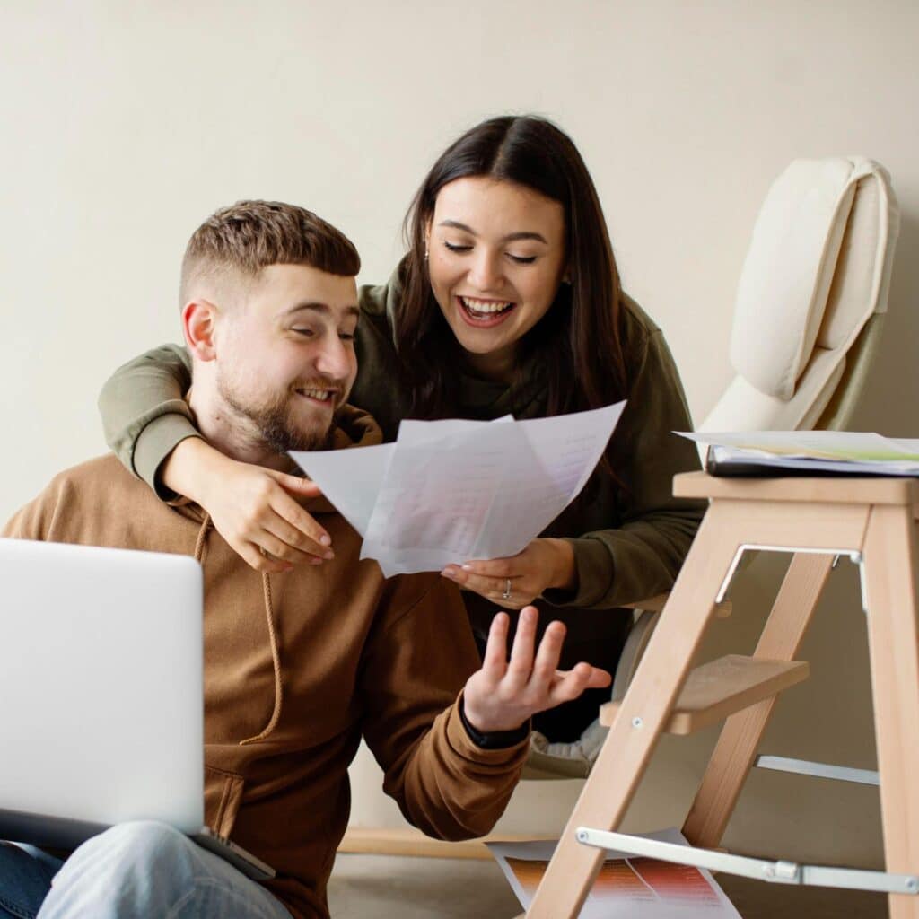A happy couple looking at house plans after buying a property with the First Home Owner Grant.