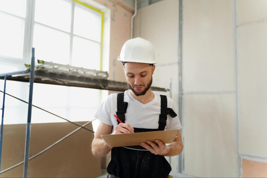 A man wearing a hard hat and completing a building inspection in a new home.
