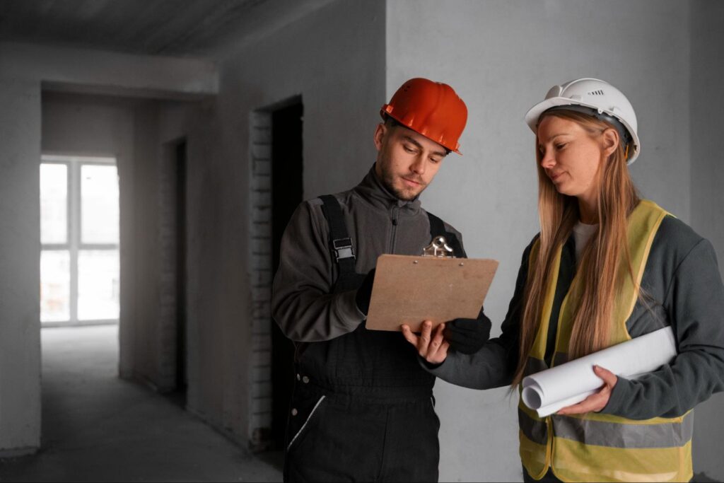 Two building inspectors wearing hardhats and completing a pre-handover inspection at a residential home